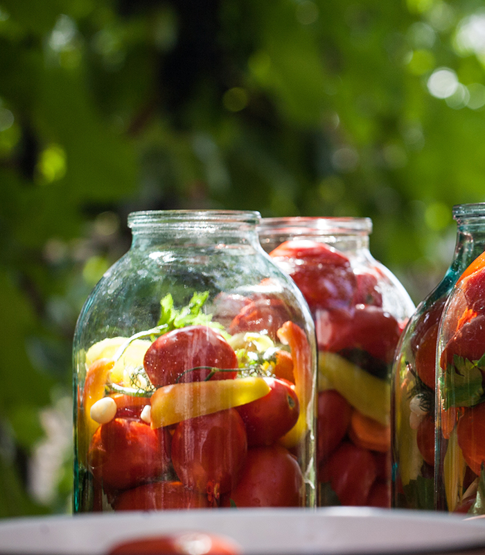 woman preparing preserved vegetables in glass jar
