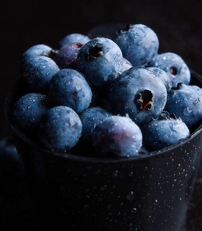 Closeup shot of blueberries in a black bowl with dark background