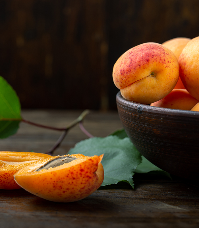 Delicious ripe apricots in a clay bowl on the table close-up.